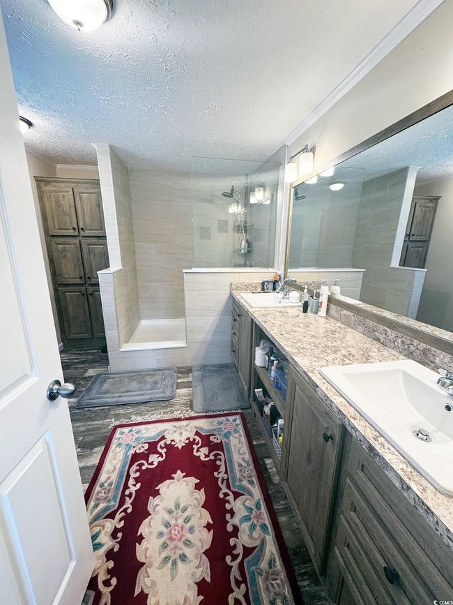Full bathroom featuring a textured ceiling, double vanity, walk in shower, and ornamental molding | Image 22