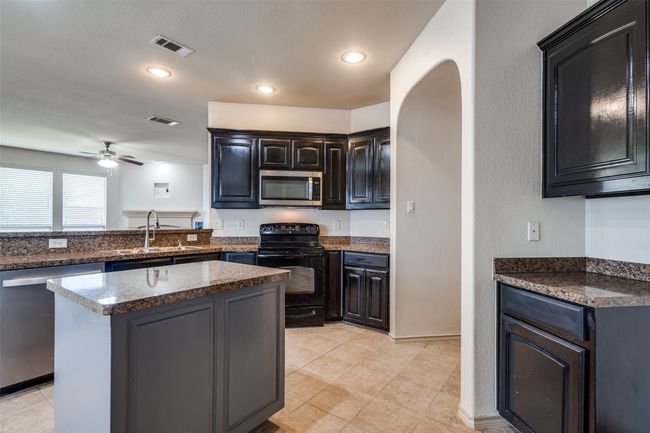 Kitchen featuring appliances with stainless steel finishes, a ceiling fan, recessed lighting, dark stone counters, and a center island | Image 14