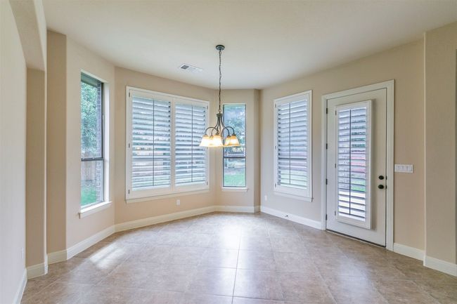Unfurnished dining area featuring light tile patterned flooring, a healthy amount of sunlight, a chandelier | Image 13