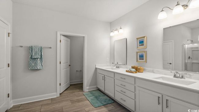 Full bath featuring double vanity, wood finished floors, a shower with shower door, and baseboards | Image 20