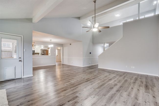 Unfurnished living room with beam ceiling, hardwood / wood-style floors, ceiling fan, and high vaulted ceiling | Image 9