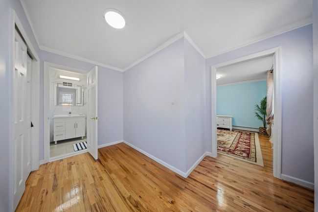 Hallway with light wood finished floors, baseboards, and ornamental molding | Image 14