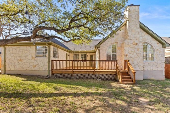 The charming backyard features a raised deck and is shaded by mature oak trees. | Image 5