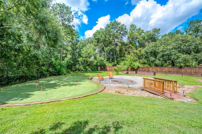 Serene backyard oasis with lush greenery, a cozy fire pit area, and a charming bridge, perfect for relaxation and entertainment. | Image 35
