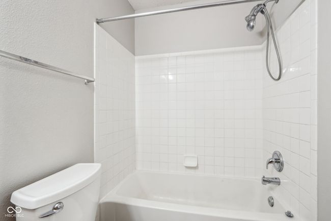 bathroom with toilet, tub / shower combination, and a textured wall | Image 33