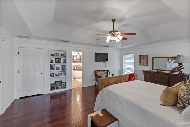 Bedroom featuring a tray ceiling, dark wood finished floors, and visible vents | Image 14