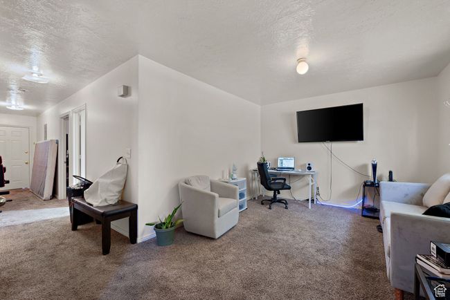 Living area with carpet floors, a desk, and a textured ceiling | Image 35