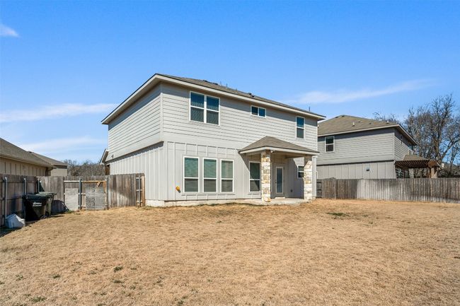 Rear view of house featuring a fenced backyard, board and batten siding, a gate, and stone siding | Image 33