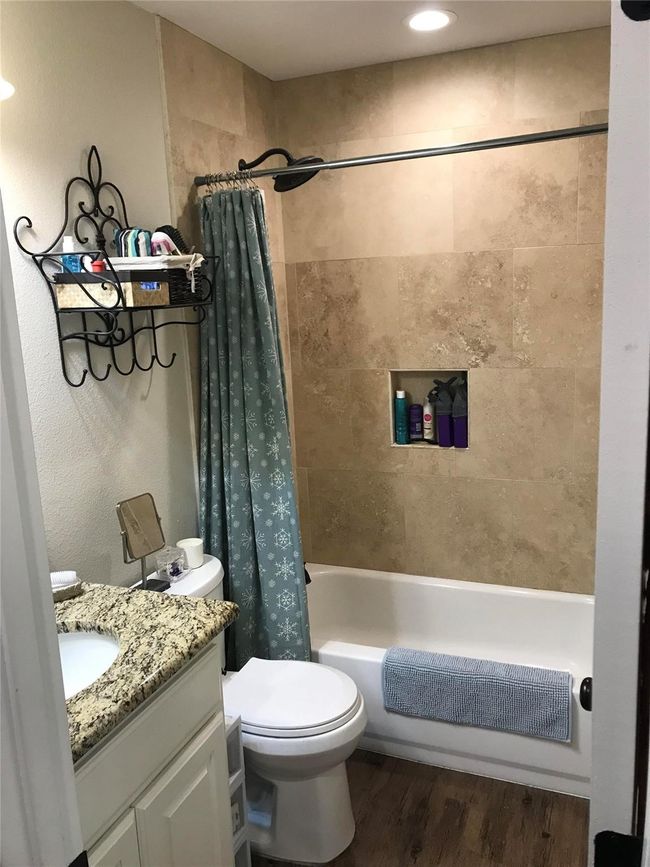 Full bathroom featuring shower / bath combo with shower curtain, toilet, vanity, and wood finished floors | Image 5