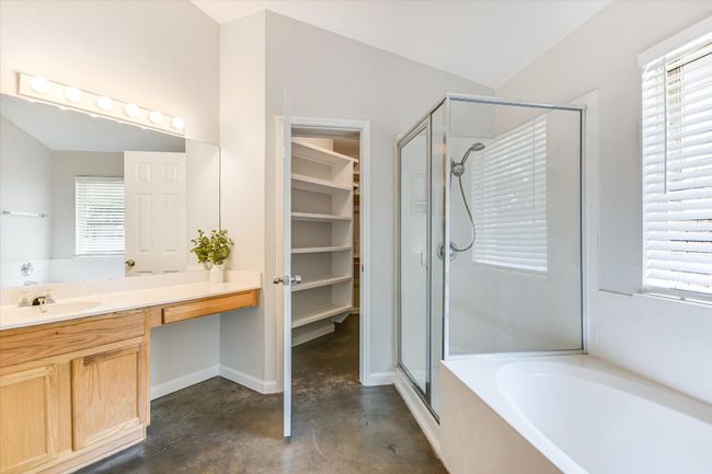 Full bathroom with a stall shower, new low flow toilet, concrete floors, a garden tub, vanity, and a walk in closet | Image 12