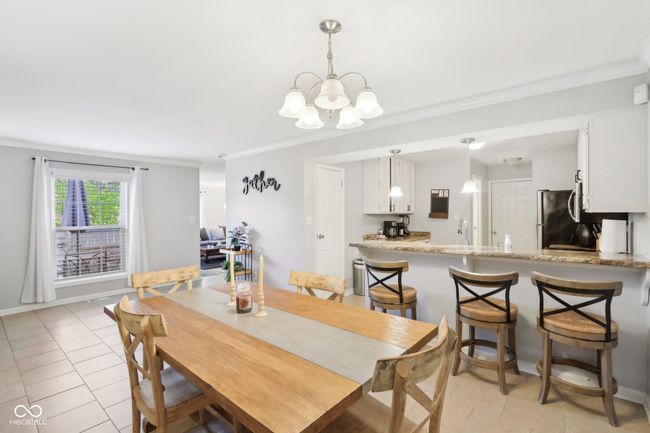 dining space featuring an inviting chandelier, crown molding, and light tile patterned floors | Image 7