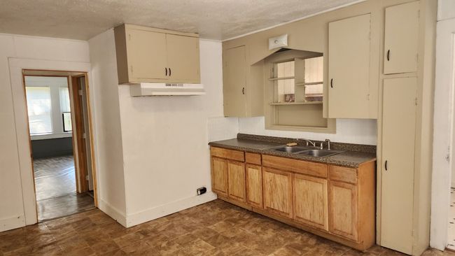 Kitchen featuring dark countertops, baseboards, under cabinet range hood, and a sink | Image 5