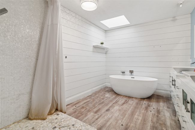 Full bath with a skylight, wood finished floors, a freestanding tub, vanity, and wood walls | Image 16