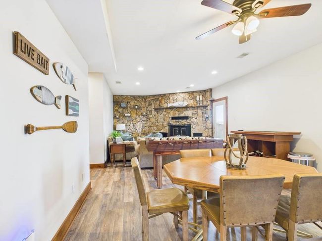 Lower level walkout with a fireplace, light wood-flooring, a ceiling fan, visible vents, and baseboards | Image 47
