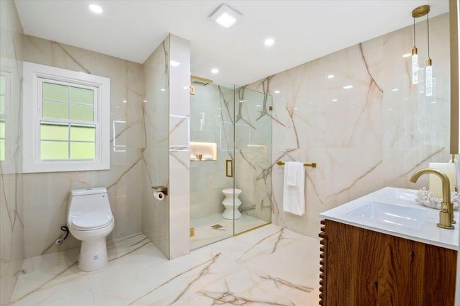 Full bath featuring marble tiled floors, vanity, a marble finish shower, and tile walls | Image 12