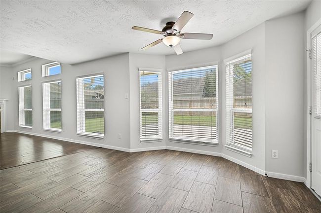 Sunlit breakfast room features a charming bay window design and tile flooring, with expansive views into the backyard and direct access to the kitchen, family room, and patio. | Image 11