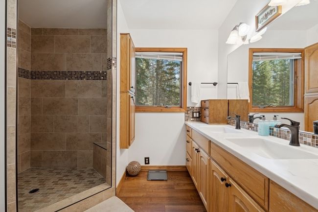 Primary bath featuring newly tiled shower, double vanity, and wood finished floors. | Image 61