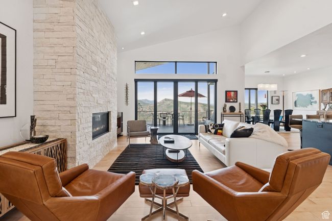 Living area with healthy amount of natural light, a stone fireplace, high vaulted ceiling, and light wood-type flooring | Image 13