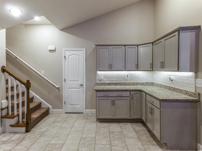 Kitchen with stone countertops, gray cabinetry, tasteful backsplash, and high vaulted ceiling | Image 14