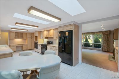 Kitchen has built in table, desk space, wall pantries and newer black appliances. | Image 3