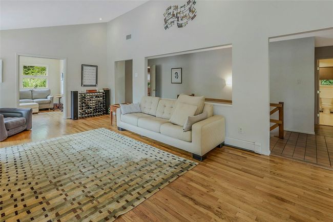 Living area featuring light wood-style flooring, high vaulted ceiling, a baseboard radiator, and baseboards | Image 11