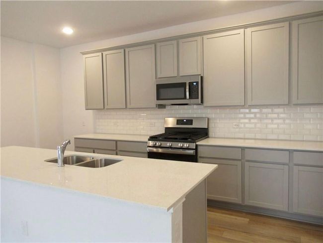Kitchen with gray cabinetry, stainless steel appliances, light wood finished floors, and recessed lighting | Image 4