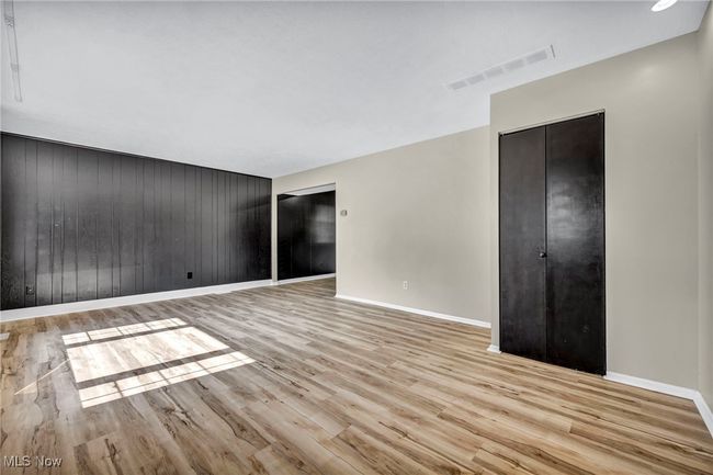 Empty room with light wood-style floors and wood walls | Image 25