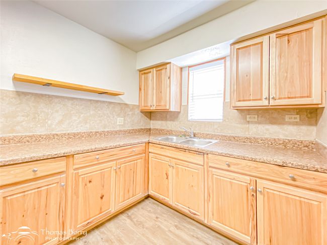 Kitchen featuring light brown cabinets, light wood finished floors, light countertops, and decorative backsplash | Image 14
