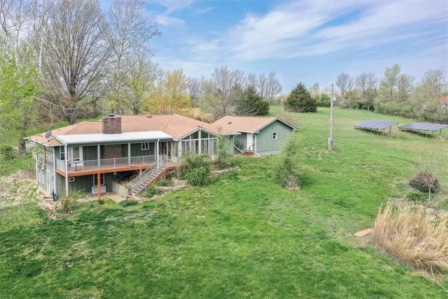 Back of property featuring a chimney, a lawn, a wooden deck, a sunroom, and stairs | Image 30