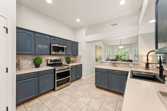 Kitchen featuring appliances with stainless steel finishes, a sink, backsplash, recessed lighting, and light countertops | Image 11