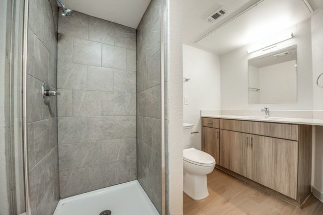 Bathroom featuring hardwood / wood-style flooring, toilet, vanity, and a tile shower | Image 34