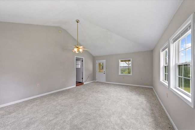 Unfurnished room with carpet floors, baseboards, lofted ceiling, and ceiling fan | Image 62