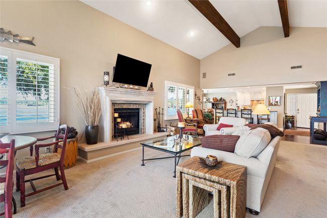 Living room with high vaulted ceiling, carpet, a warm lit fireplace, beamed ceiling, and recessed lighting | Image 8