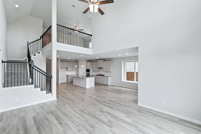 Unfurnished living room with ceiling fan, light wood-type flooring, stairs, and high vaulted ceiling | Image 12