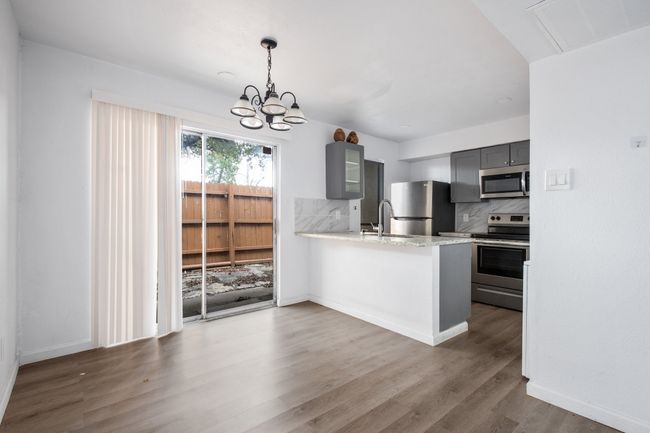 Kitchen with appliances with stainless steel finishes, backsplash, gray cabinets, kitchen peninsula, and a chandelier | Image 9