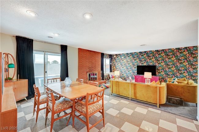 Dining space with a brick fireplace, light floors, a textured ceiling, and wallpapered walls | Image 11