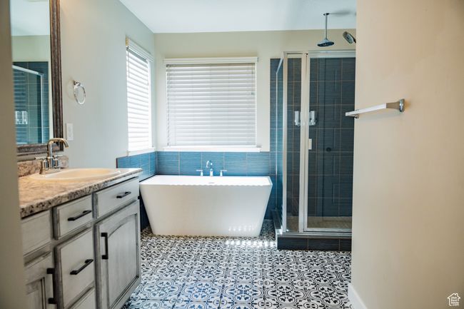 Full bathroom featuring a shower stall, vanity, a freestanding tub, and tile patterned flooring | Image 16