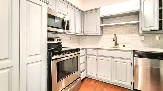 Kitchen with tasteful backsplash, appliances with stainless steel finishes, light hardwood / wood-style floors, and sink | Image 11