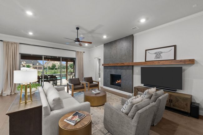 Open living area highlighted by grand slider doors, crown molding, a ceiling fan, recessed lighting, and modern fireplace | Image 8