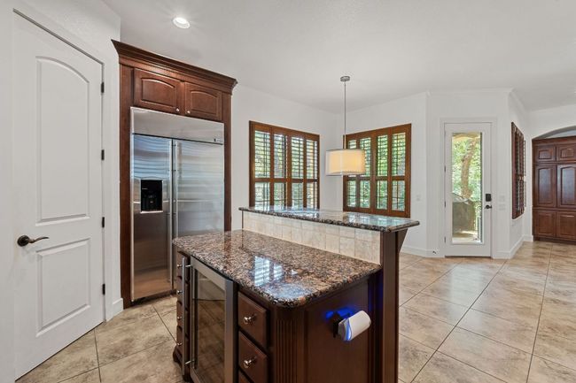 Kitchen with built in refrigerator, wine cooler, a center island, dark stone countertops, and healthy amount of natural light | Image 16