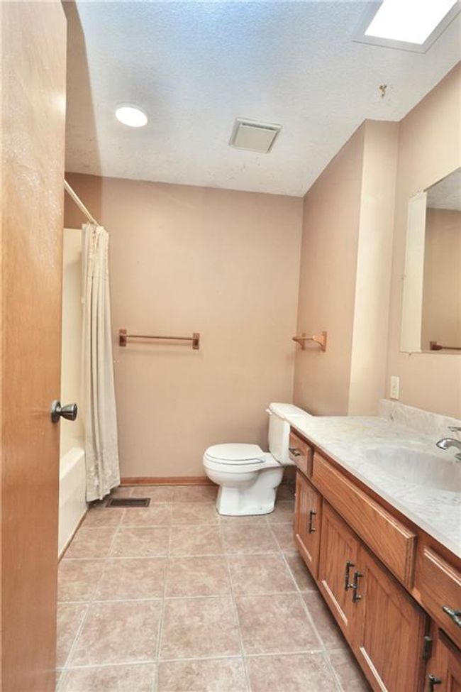 Bathroom with vanity, shower / tub combo, tile patterned flooring, and a skylight | Image 21
