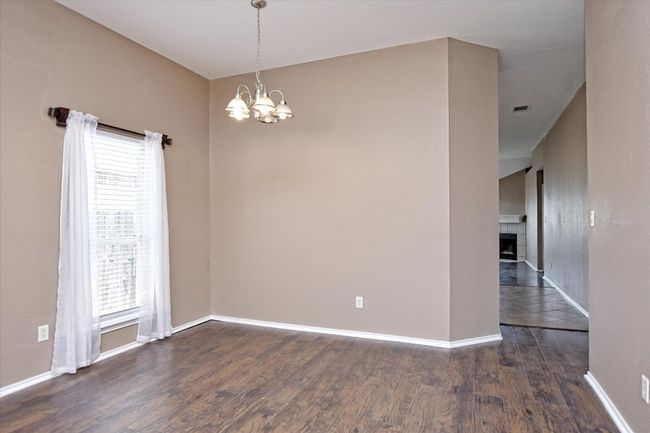 Spare room featuring a chandelier, wood finished floors, healthy amount of natural light, and baseboards | Image 7