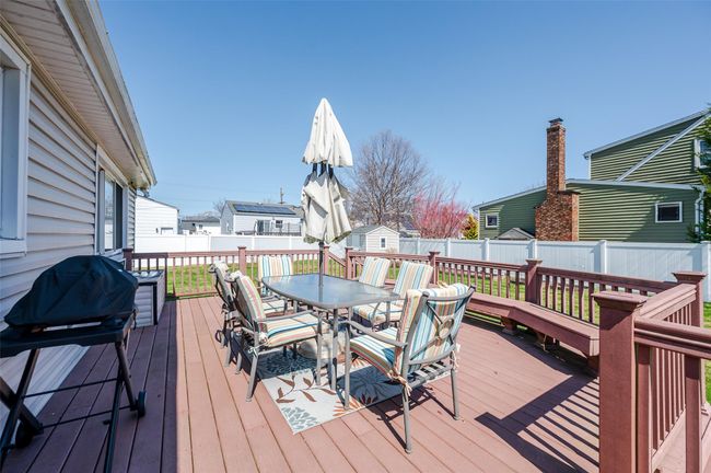 Wooden terrace with a fenced backyard, outdoor dining area, an outbuilding, and a storage shed | Image 18