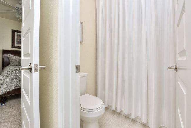 Full bath with tile patterned floors, toilet, a shower with curtain, and a ceiling fan | Image 15