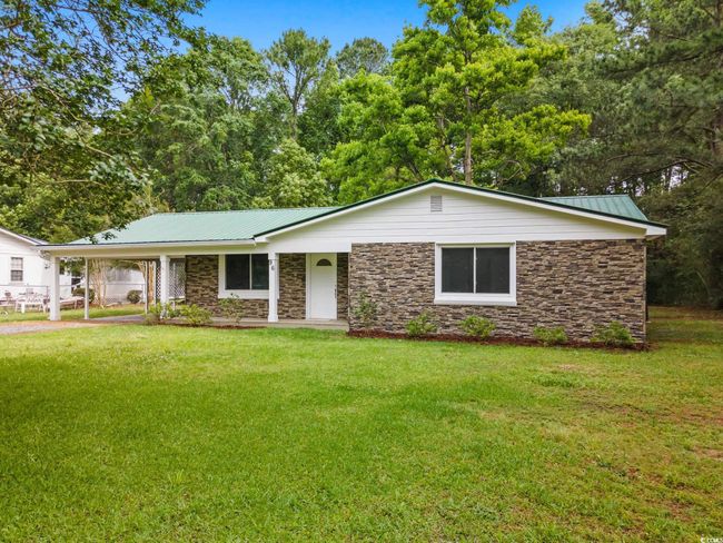 View of front of home featuring stone siding, a front yard, metal roof, and a carport | Image 11