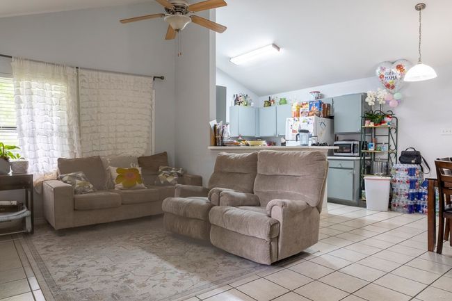 Living room with light tile patterned flooring, ceiling fan, and high vaulted ceiling | Image 6