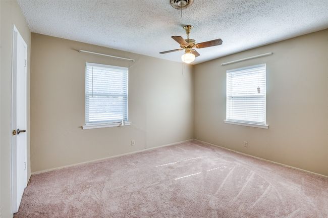 Carpeted empty room featuring ceiling fan, plenty of natural light, and a textured ceiling | Image 17