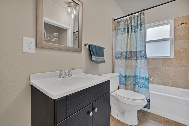 Another full bathroom in between the two bedrooms, featuring vanity, tile patterned flooring, shower / bath combo, and toilet. Utility Closet in this bathroom | Image 19