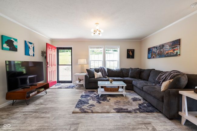 living area featuring crown molding, a chandelier, wood finished floors, and baseboards | Image 7