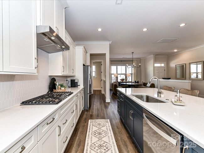 Kitchen offers quartz counters, stainless steel appliances, gas cook top, huge 8' island, custom lighting, plenty of cabinets for storage & pantry! | Image 8